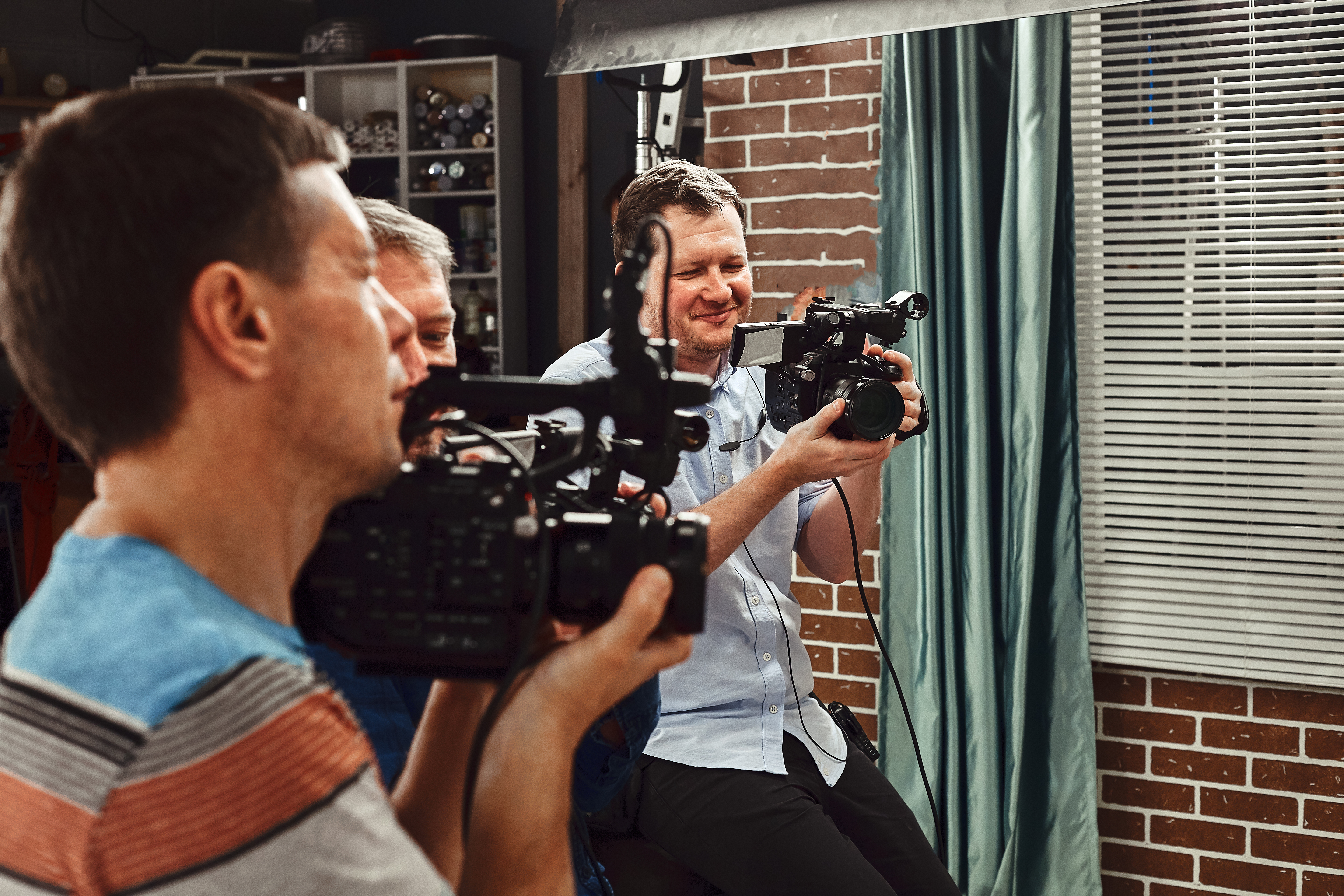 Video production backstage. Behind the scenes of creating video content, a professional team of cameramen with a director filming commercial ads. Video content creation, video creation industry.